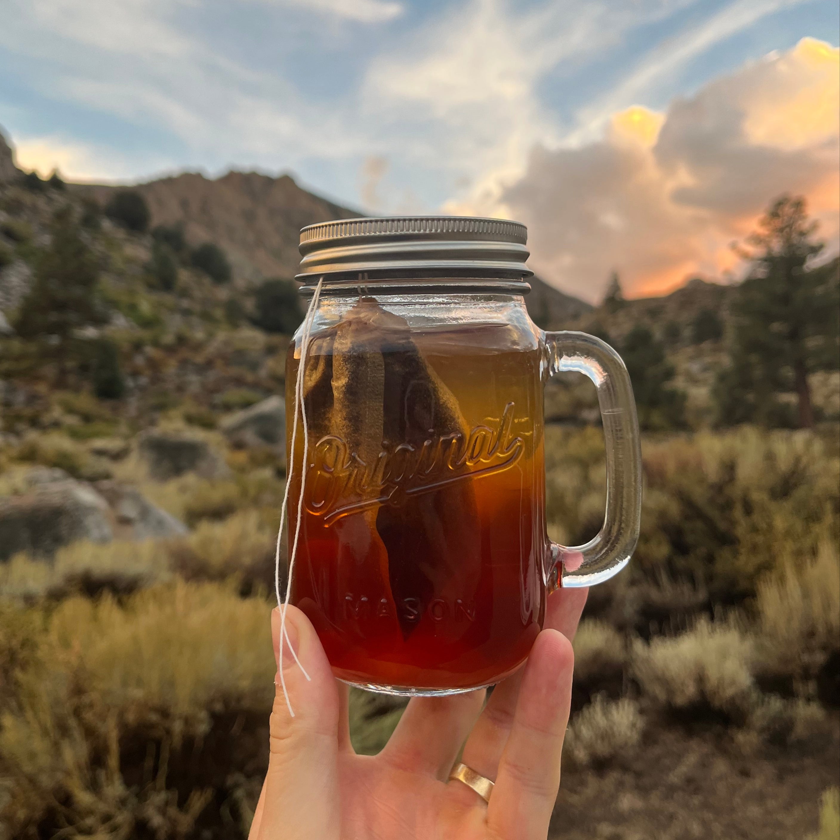 Bear box brew in a mason jar with a sunset in the background.