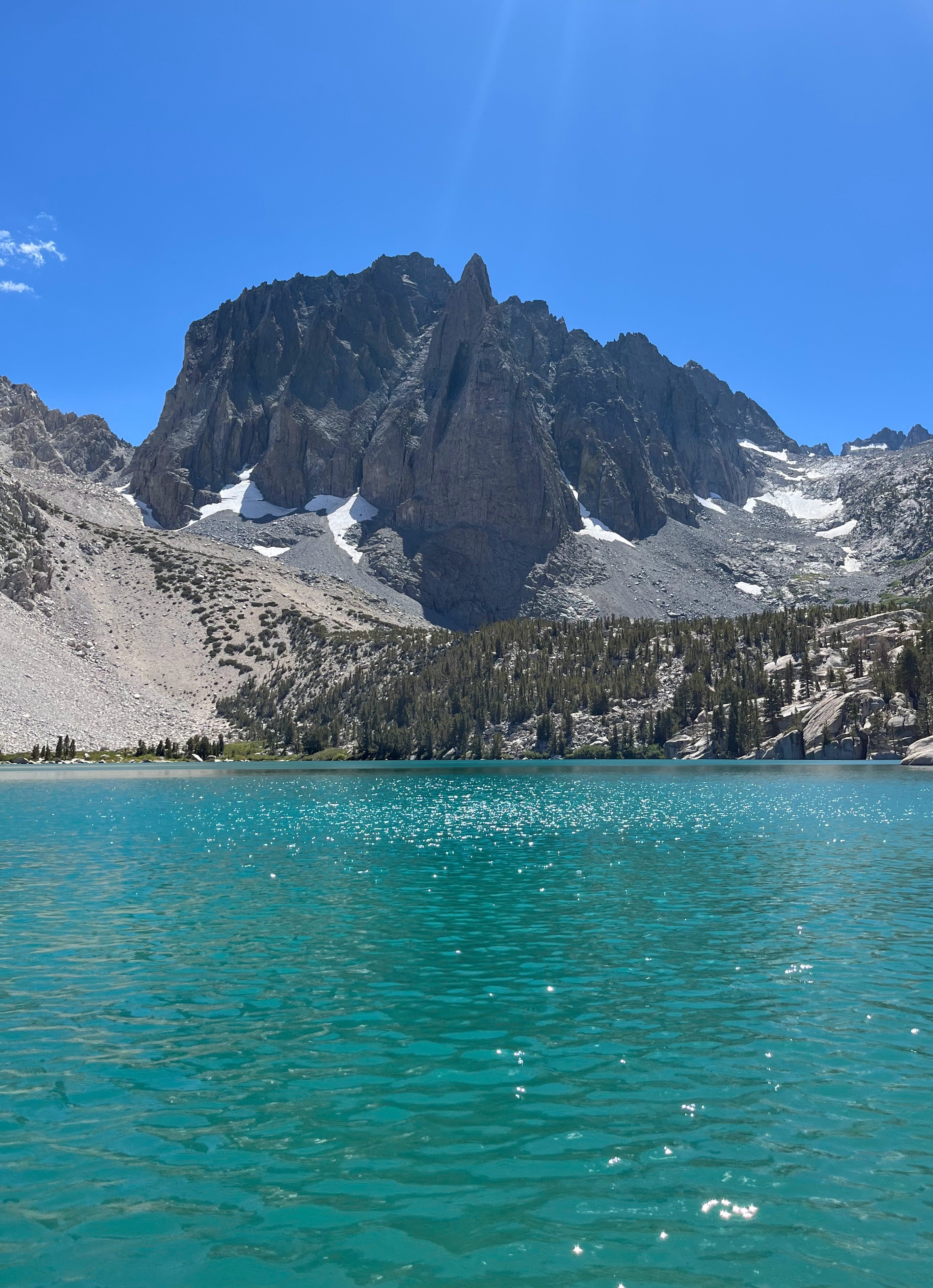 A glistening emerald green lake with a mountain peak in the background.