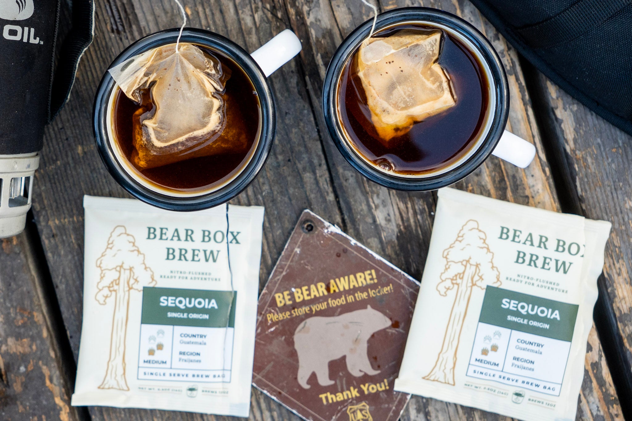 Bear Box brew bags steeping in two mugs on a picnic table